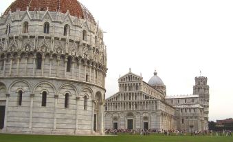 a grassy field with a group of people gathered around a large building , possibly the leaning tower of pisa at Easy Space