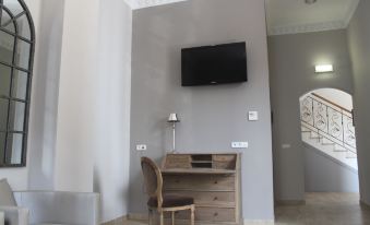 a small room with a wooden desk and chair , a television on the wall , and a staircase at Hotel Villa Maria