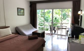 a bedroom with a bed , couch , and sliding glass door leading to a patio area at Chanthaburi Garden Hotel