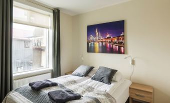 a cozy bedroom with a large bed and a painting of a city skyline above the bed at Town Square Apartments