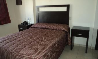 a bed with a brown blanket and black headboard is in a room next to a desk at Hotel San Francisco