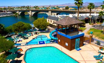 a large swimming pool with a brown roof is surrounded by palm trees and buildings at London Bridge Resort