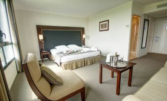 a spacious hotel room with a large bed , a chair , and a dining table in the living area at Hotel du Golf