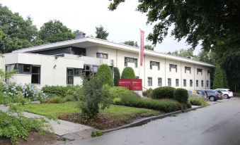 a large white building with a red sign and a red fire hydrant in front of it at Bastion Hotel Bussum Hilversum