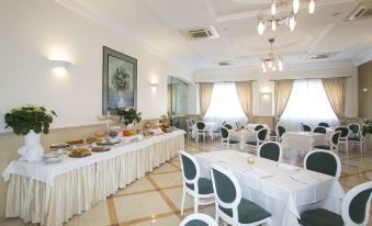 a large dining room with multiple tables and chairs , as well as a buffet table filled with food at Hotel Cavaliere