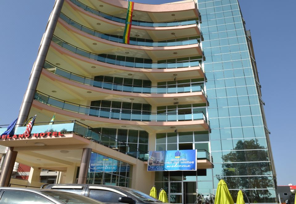 a tall building with many windows and a car parked in front of it , under a clear blue sky at Delano Hotel Bahir Dar