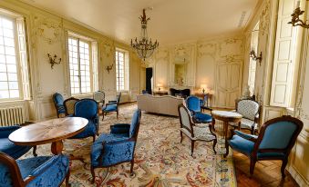 a large , ornate room with multiple chairs and couches arranged around a dining table , creating a cozy and inviting atmosphere at Chateau d'Audrieu