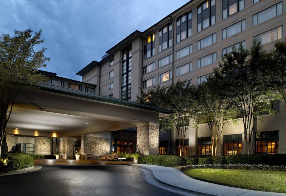 a large hotel building surrounded by trees , with a parking lot in front of it at Atlanta Marriott Alpharetta
