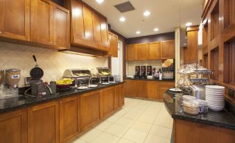 a well - equipped kitchen with wooden cabinets , granite countertops , and various appliances such as a microwave , toaster , and coffee maker at Sonesta ES Suites Phoenix Goodyear