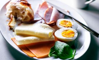 a white plate filled with an assortment of food items , including meats , cheese , and eggs at SpringHill Suites Athens West