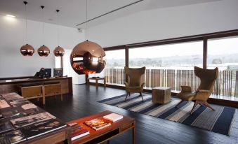 a modern living room with wooden furniture , a large copper sphere hanging from the ceiling , and a view of the city outside at L'And Vineyards