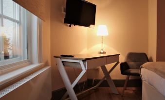 a desk with a lamp and chair in a room with a television mounted on the wall at Rioshouse George-Inn