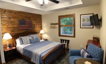 a cozy bedroom with wooden walls , blue bedding , and a tv mounted on the wall at Walnut Waters Bed & Breakfast