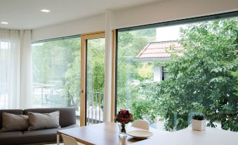 a modern living room with large windows , wooden floors , and a dining area with a table and chairs at Lumina Apartments