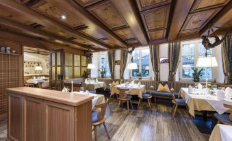 a large dining room with wooden floors and a high ceiling , filled with people enjoying their meals at Hotel Gruner Baum