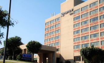 a large hotel building with multiple floors , surrounded by trees and located on a street at Riverview Inn