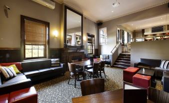 a spacious room with a dining table , chairs , and couches , along with a staircase in the background at Nightcap at Pymble Hotel