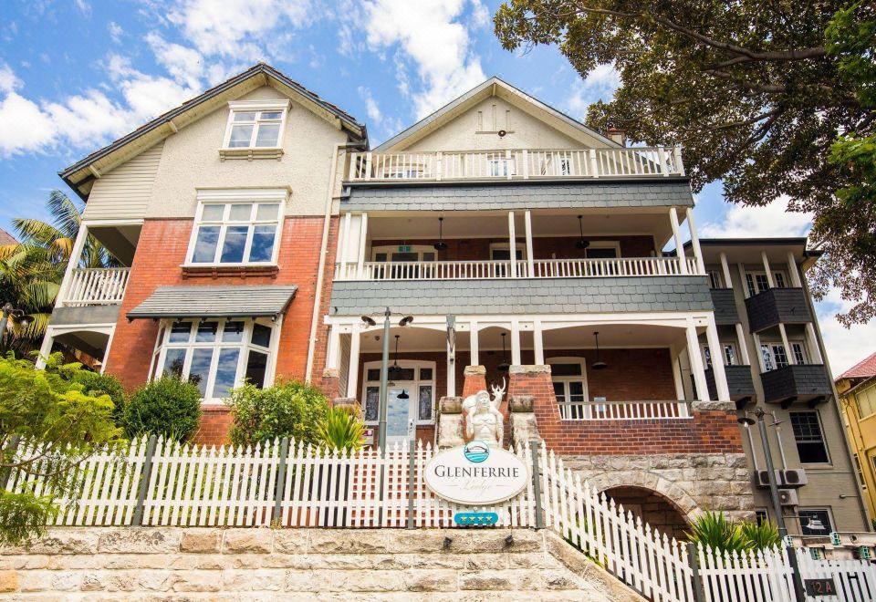 a large , two - story house with a white picket fence and stairs leading up to it at Glenferrie Lodge
