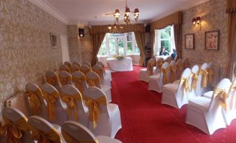 a well - decorated wedding ceremony room with white and gold chairs arranged in rows , ready for guests at Woodlands Hotel