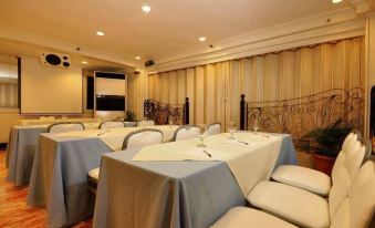 a conference room with chairs arranged in rows and a projector on the wall , providing natural light at Executive Hotel