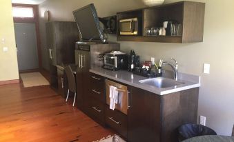 a kitchen with wooden cabinets and a sink , featuring a television mounted on the wall at Desert Pearl Inn