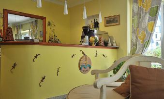 a cozy living room with yellow walls , a comfortable couch , and a bar area decorated with birds on the wall at Hotel Miramare