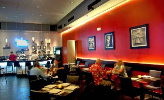 a group of people are sitting in a restaurant with red walls and artwork on the walls at Hotel Principe