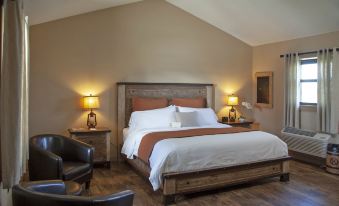 a cozy bedroom with a large bed , two nightstands , and a chair in the corner at OK Corral
