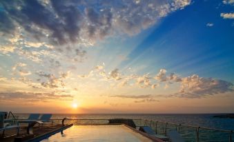 a pool overlooks the ocean at sunset with a beautiful sky and clouds in the background at Hotel Belvedere