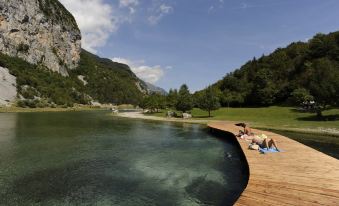 a group of people relaxing by a wooden boardwalk next to a lake , enjoying the sunny day at Miravalle