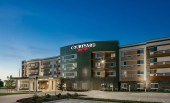 "a modern , green building with the word "" courtyard "" prominently displayed , surrounded by trees and a parking lot" at Courtyard Omaha Bellevue at Beardmore Event Center