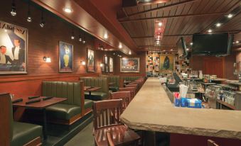 a well - lit restaurant with wooden tables and chairs , along with a bar area where people are sitting at Holiday Inn Carbondale-Conference Center