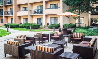 an outdoor patio area with various seating options , including couches , chairs , and a dining table at Courtyard Chicago Wood Dale / Itasca