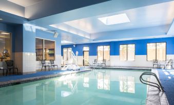 an indoor swimming pool with a blue and white color scheme , surrounded by chairs and tables at Courtyard Seattle Federal Way