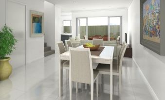 a modern living room and dining area with a white table , chairs , and a large window at Direct Collective - Breeze on Brightwater