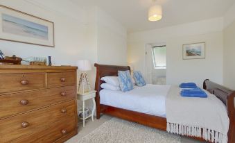 a spacious bedroom with a large bed , a dresser , and a door leading to a bathroom at The Porthole