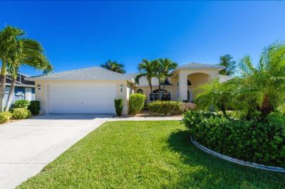 a large , well - maintained white house with a well - maintained lawn and palm trees in the front yard at Italy