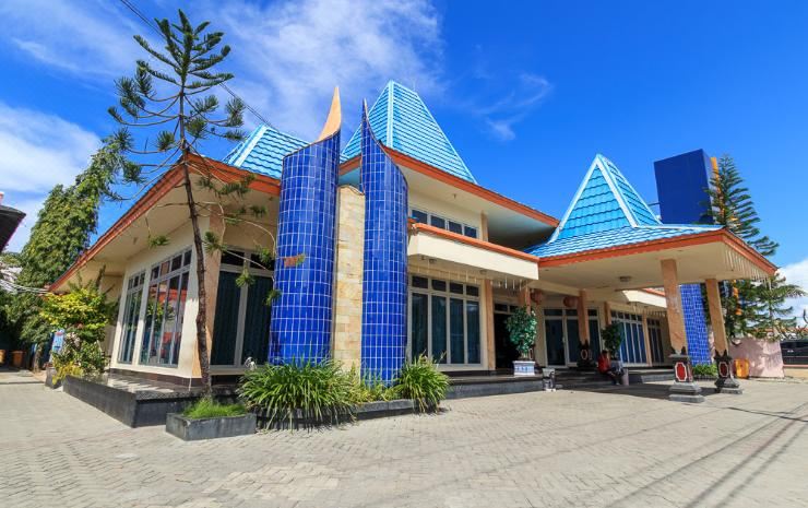 a modern building with blue glass towers and a large entrance , surrounded by trees and plants at Hotel Elvin