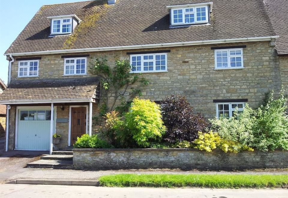 a brick house with a stone foundation , situated on a street corner with a mailbox nearby at Stone House