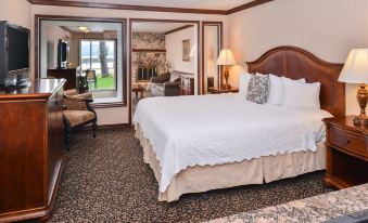 a large bed with a wooden headboard and white linens is in a room with a chair , desk , and window at Best Western Edgewater Resort