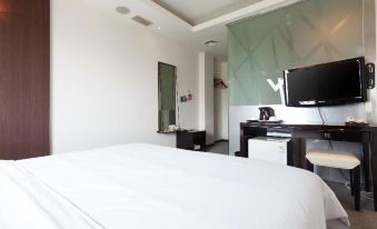 a modern bedroom with white walls , a large bed , and a flat - screen tv mounted on the wall at The Riverside Hotel