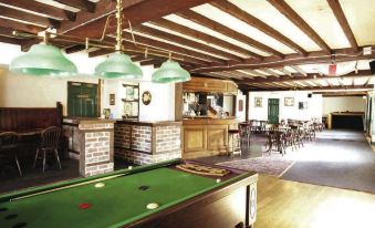 a pool table with green felt is in a room with brick walls and wooden beams at Malt House