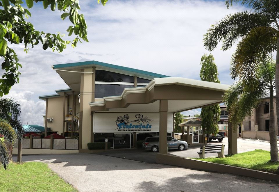 a building with a car parked in front of it and a blue sign above the entrance at Tradewinds Hotel
