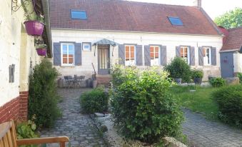 a beautiful house with blue shutters and a white roof , surrounded by a well - maintained garden at La Grenouillère