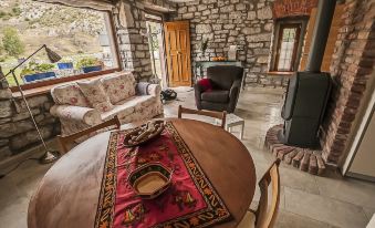 a cozy living room with stone walls , wooden furniture , and a dining table surrounded by chairs at El Lucero