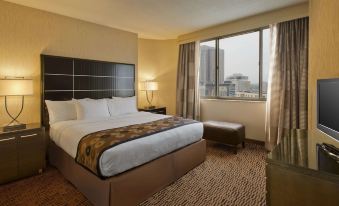 a hotel room with a king - sized bed , a large window , and a view of the city at DoubleTree Suites by Hilton Minneapolis