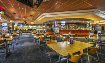 a large restaurant with multiple dining tables and chairs , as well as a bar in the background at Nightcap at Matthew Flinders Hotel