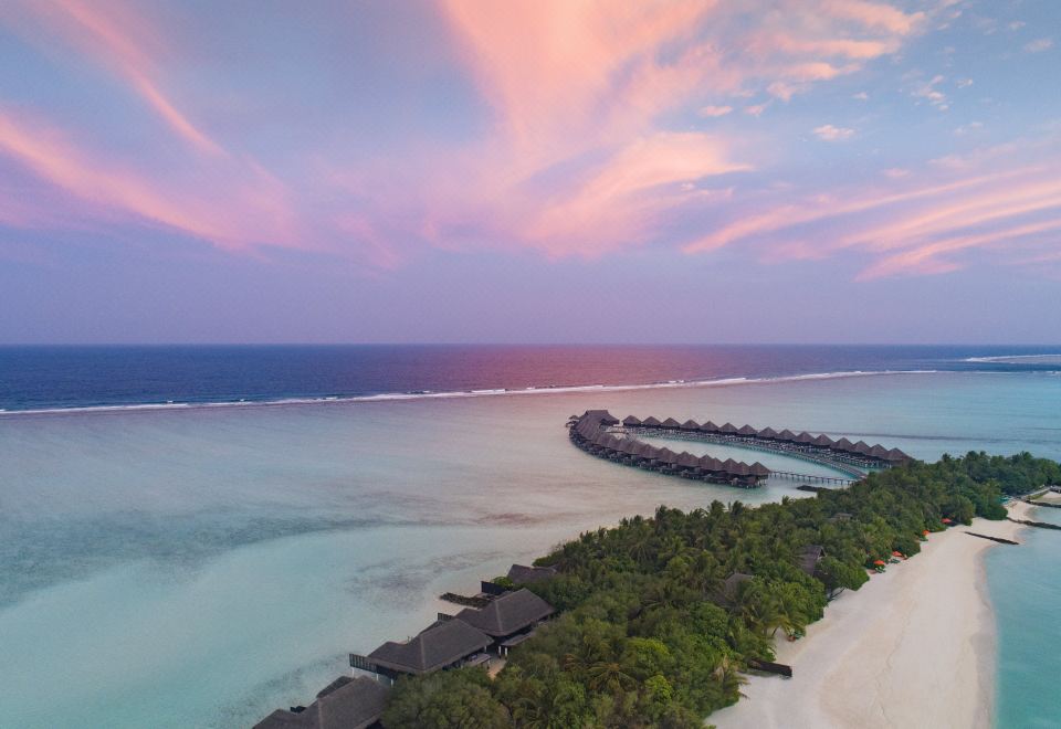 a beautiful beach with a sunset view and a resort surrounded by trees , creating a serene and tranquil atmosphere at Taj Exotica Resort & Spa