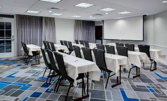 a conference room with rows of tables and chairs , a projector screen , and a podium at Residence Inn Richmond Chester