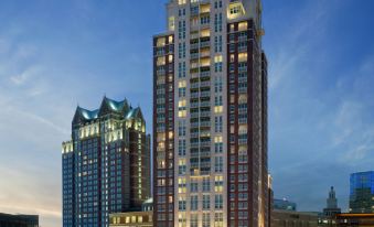 a tall , modern building with multiple stories and a large roof , situated in a bustling city at dusk at Omni Providence Hotel
